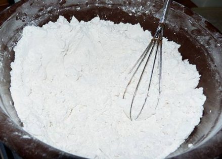 Brown mixing bowl almost full of flour mix with whisk.