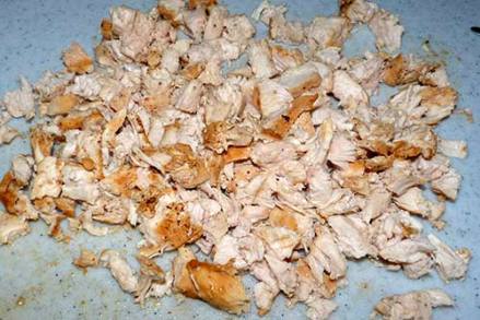 Chopped up cooked chicken breast on a cutting board.