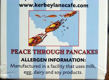 The side of the Kerbey pancake mix box has the slogan Peace Through Pancakes and graphic of flying pancakes above their allergen information.