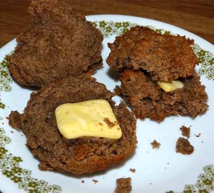 Two buckwheat sorghum biscuits cut open with butter on a small plate.